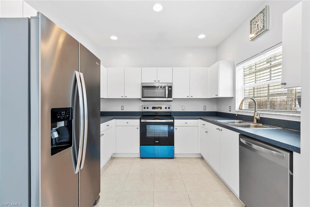 U-shaped kitchen featuring white cabinetry, stainless steel appliances, dark countertops, and recessed lighting