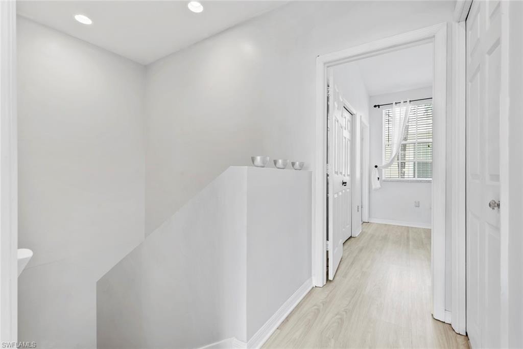 Recessed ceiling lighting illuminating a hallway with light wood-finish flooring