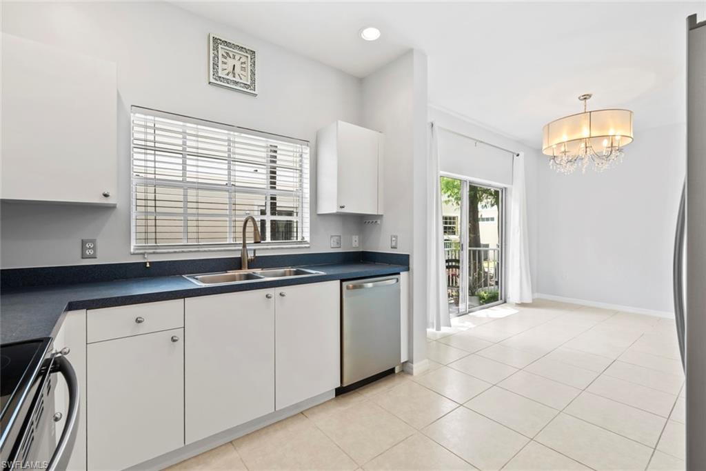 Kitchen featuring white cabinetry, dark countertops, a stainless steel sink with a gooseneck faucet, and a stainless steel dishwasher