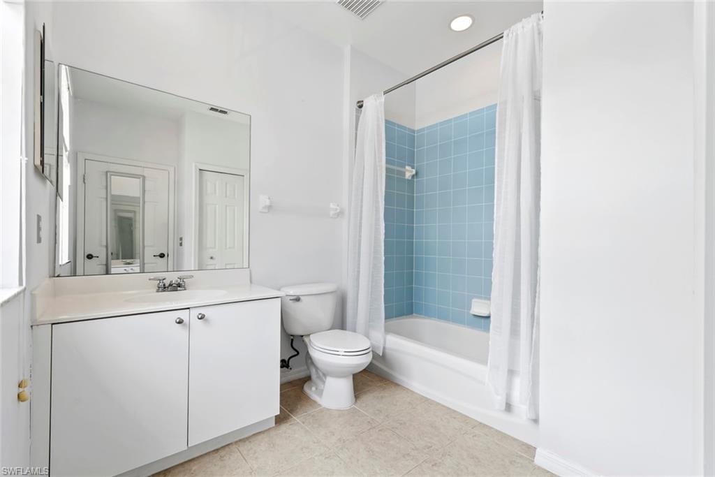 White vanity with a single basin sink, large wall-mounted mirror, and tile flooring