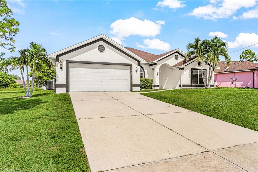 White exterior with dark trim accents, attached garage with a white door, concrete driveway, and a manicured lawn