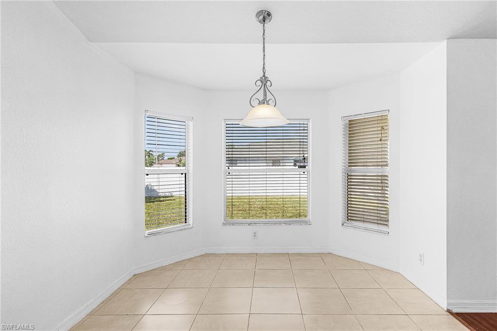 Recessed ceiling with a hanging pendant light fixture, three large windows, and tile flooring