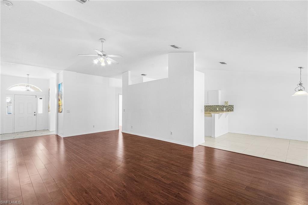 Wood-finish flooring, white walls, ceiling fan, tile flooring, and a decorative pendant light