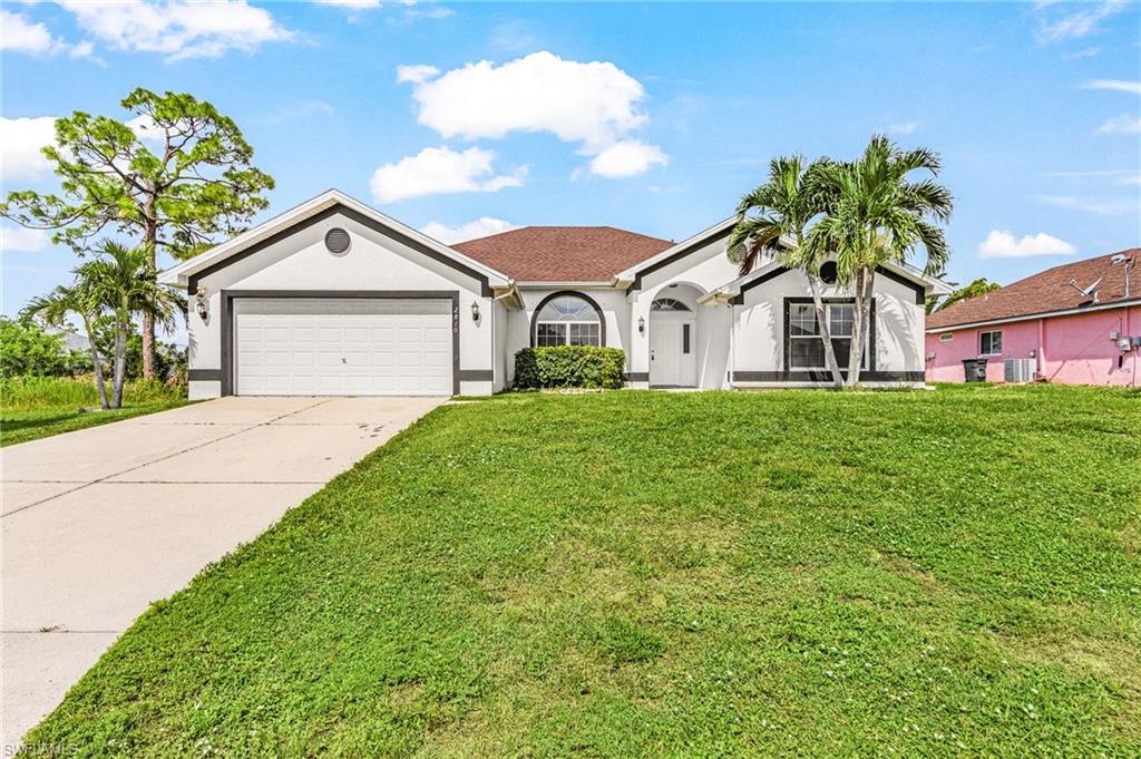 Single-story stucco exterior with a two-car garage, arched entry, and mature palm trees