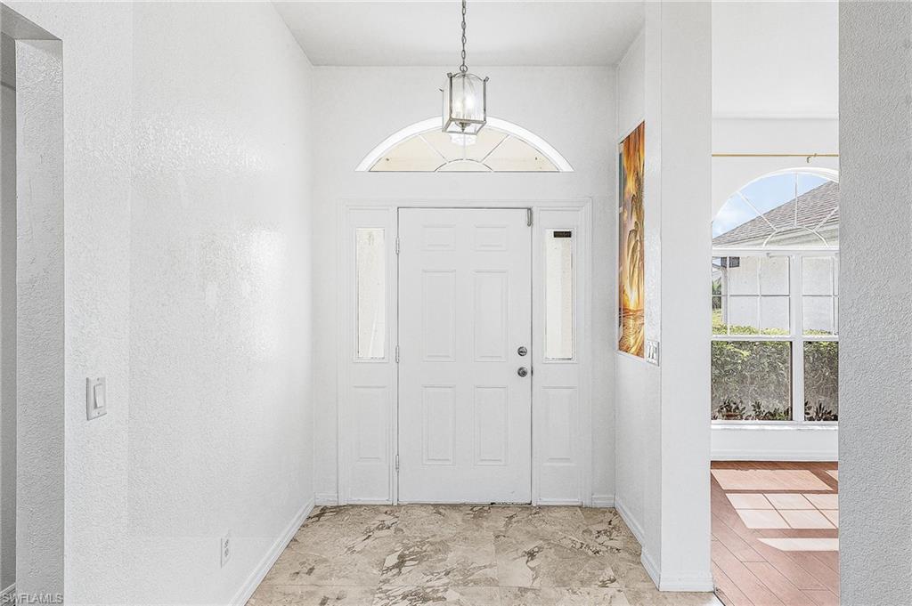 Entryway featuring a decorative pendant light, a transom window, sidelight windows, and stone-finish flooring