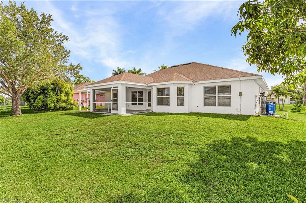 Expansive green lawn with a screened-in patio and multiple windows