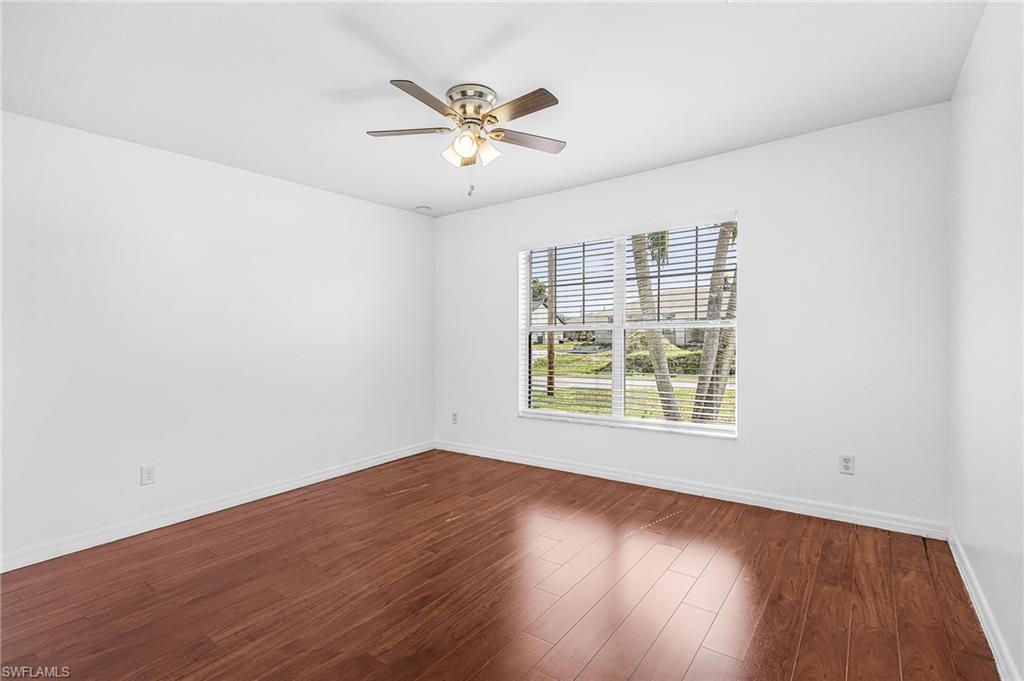 Hardwood-finish flooring, white walls, ceiling fan with integrated lighting, and a large window with horizontal blinds