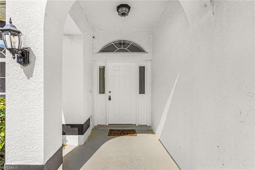 Arched entryway with a recessed light fixture and a wall-mounted coach light