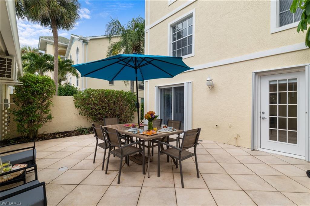 Expansive private patio with large format tile flooring, stucco walls, and mature landscaping
