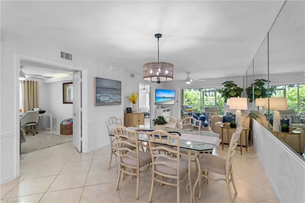 Open-concept living space with tile flooring, a glass-top dining table, and a contemporary chandelier