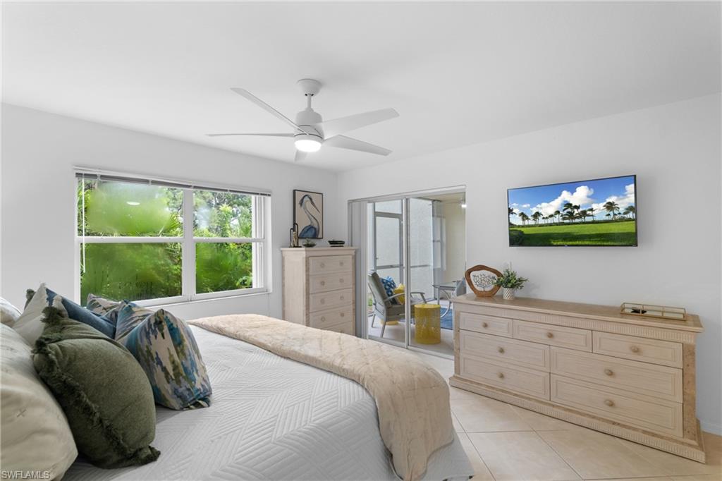Ceiling fan with integrated lighting, large window with outdoor scenery, sliding glass door leading to screened patio, tiled flooring, and neutral wall finishes