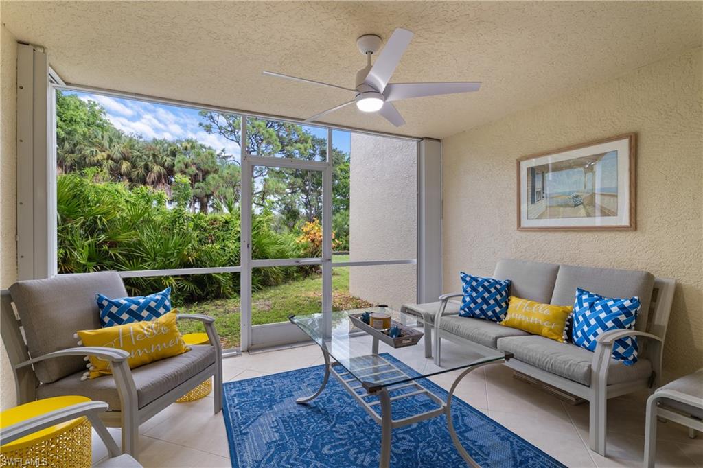 Screened lanai featuring a ceiling fan with integrated lighting, textured wall finish, and tiled flooring