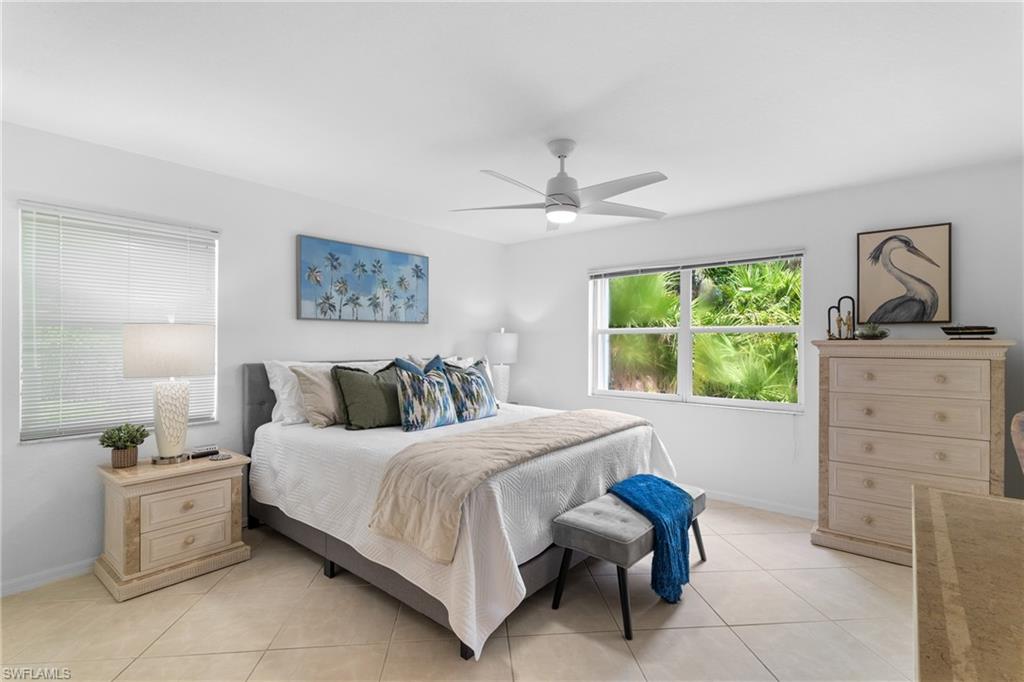 Neutral wall paint, tile flooring, window with a green outdoor backdrop, ceiling fan with integrated lighting