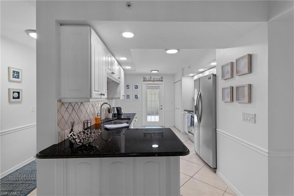Kitchen featuring white cabinetry, dark stone countertops, stainless steel appliances, and a tile backsplash