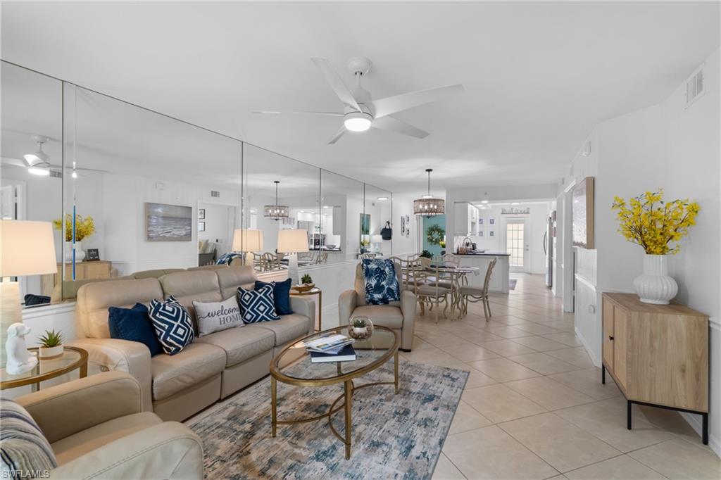 Open-concept living area featuring a ceiling fan, wall-to-wall mirrors, and tile flooring