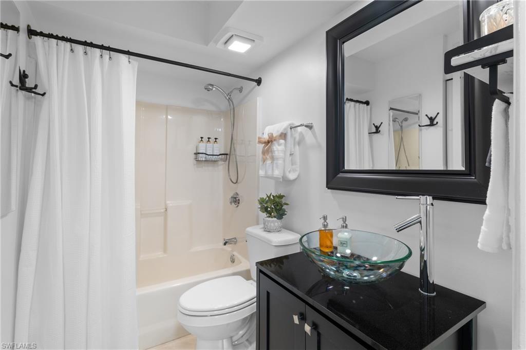 Bathroom featuring a tub/shower combination, dark wood-finish vanity with a vessel sink, and a framed wall mirror