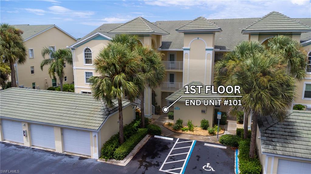 Multi-story stucco exterior featuring arched windows, tile roofing, and mature palm trees
