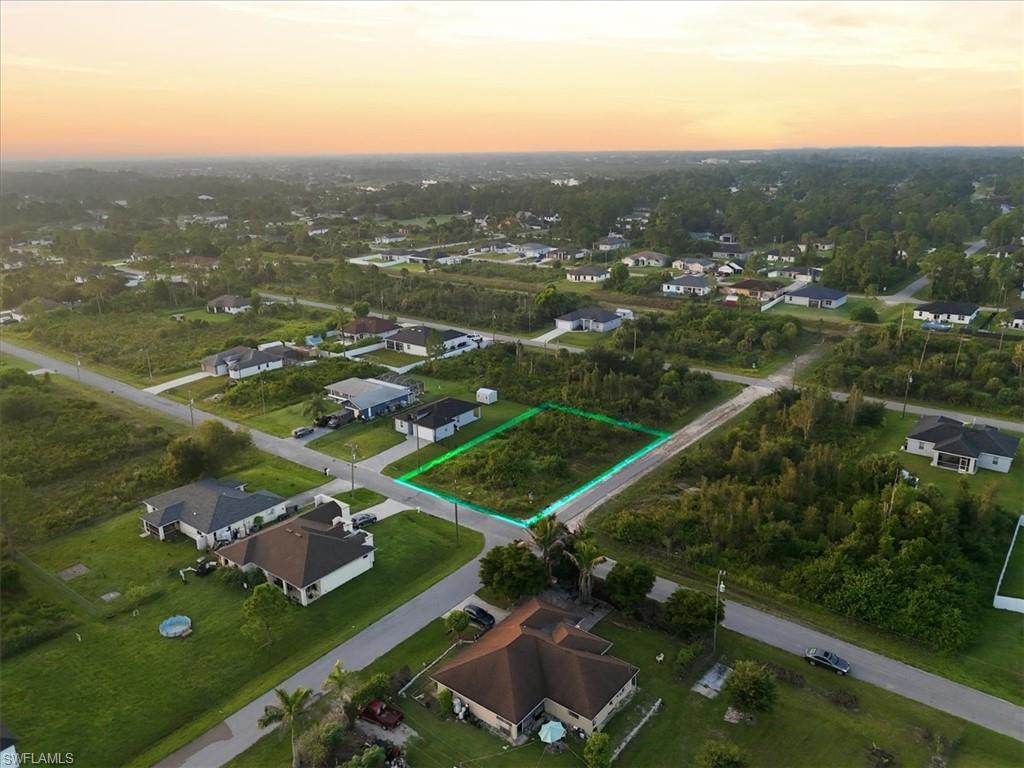 Vacant corner lot with surrounding residential properties, bordered by paved roadways
