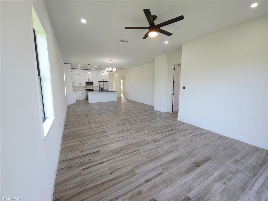 Spacious open-concept layout featuring wood-finish flooring, recessed lighting, a modern ceiling fan, and a kitchen island with pendant lighting