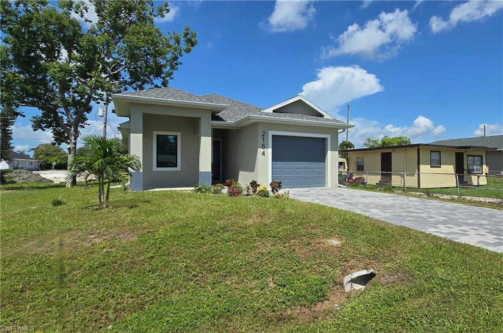 Contemporary single-story residence featuring a gray exterior, attached garage with a gray door, and a paved driveway