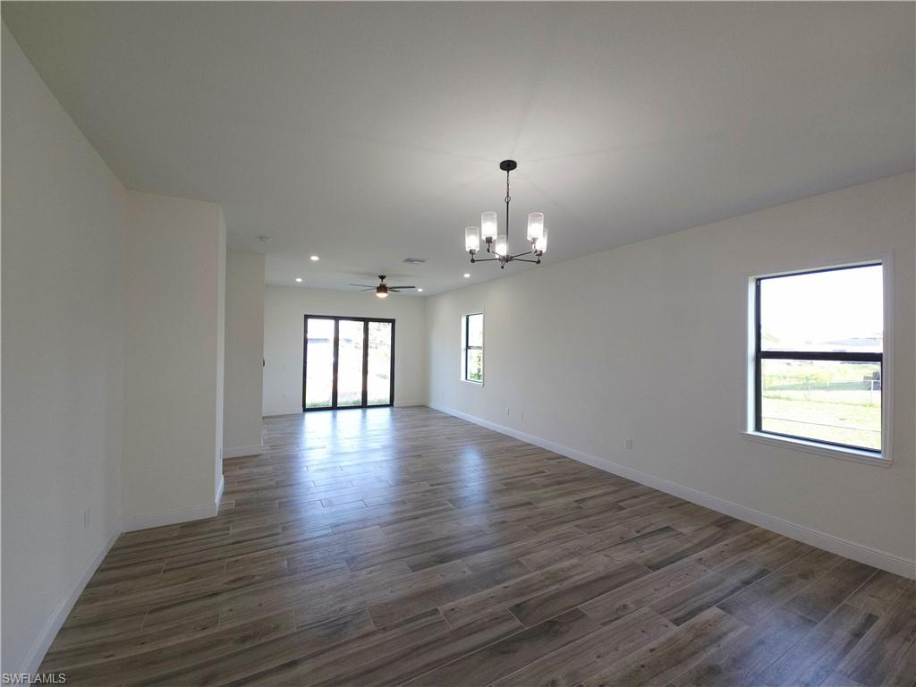 Recessed lighting, a modern chandelier, wood-finish flooring, and sliding glass doors