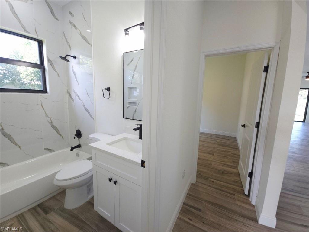 Bathroom featuring a white vanity with a rectangular sink, black fixtures, and a shower/tub combination with tiled walls