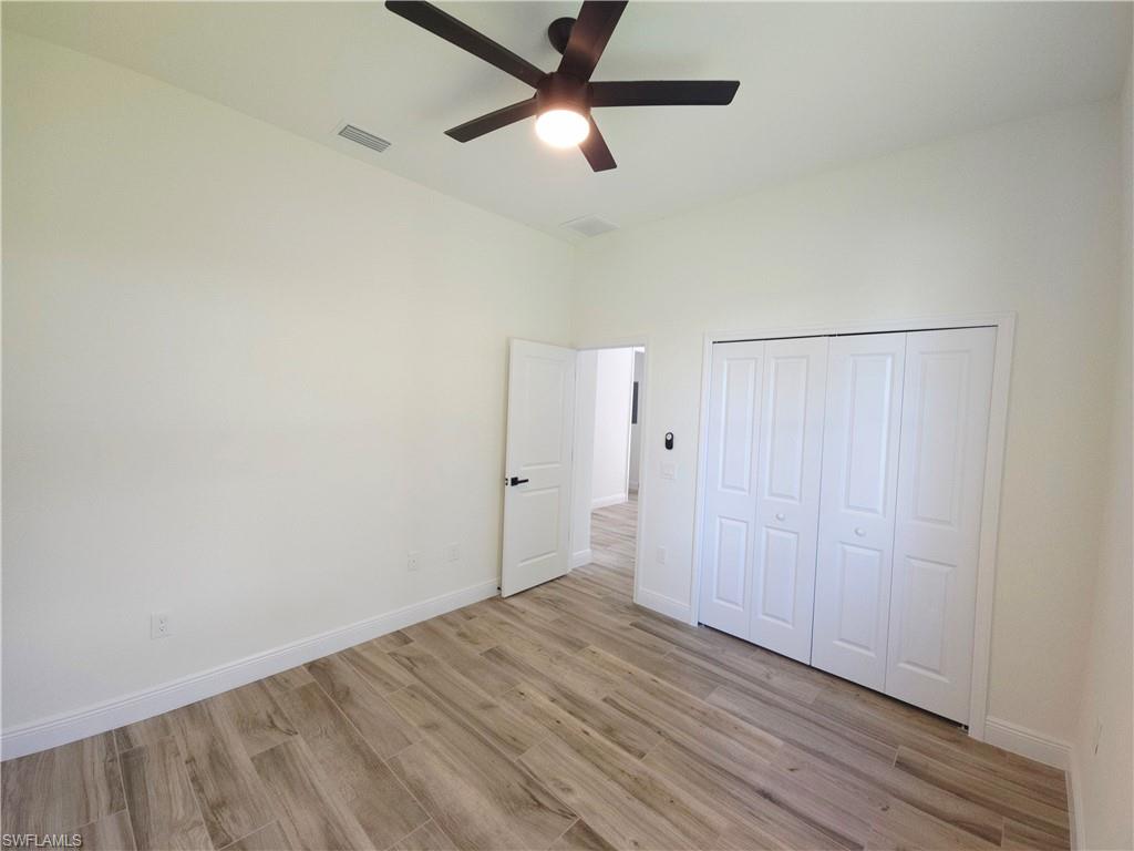 Bedroom 2, Wood-finish flooring, white walls, and a ceiling fan with integrated lighting