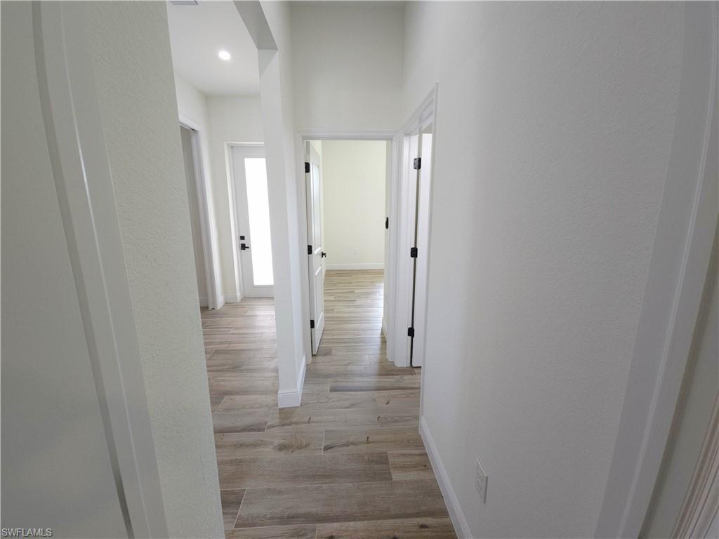 Hallway featuring wood-finish flooring, white walls, and recessed lighting