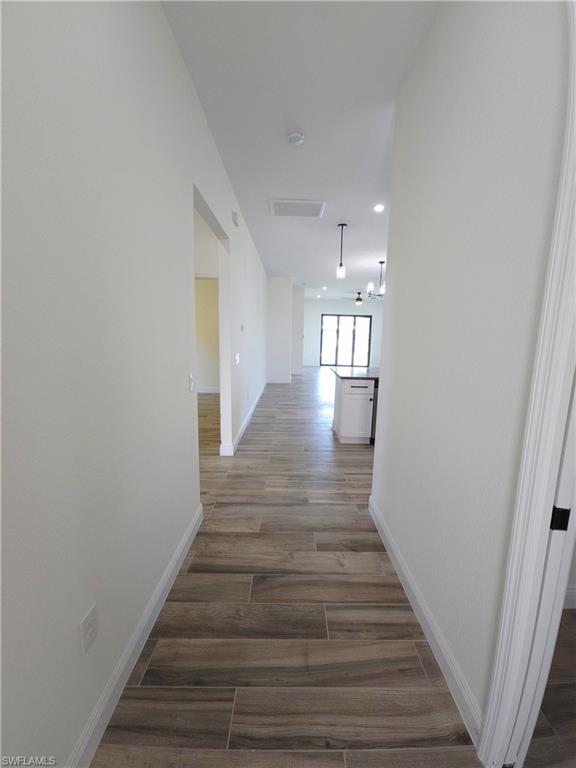 Wood-finish flooring, recessed lighting, and modern pendant fixtures