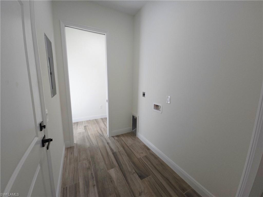 Wood-finish flooring, white baseboards, and white walls