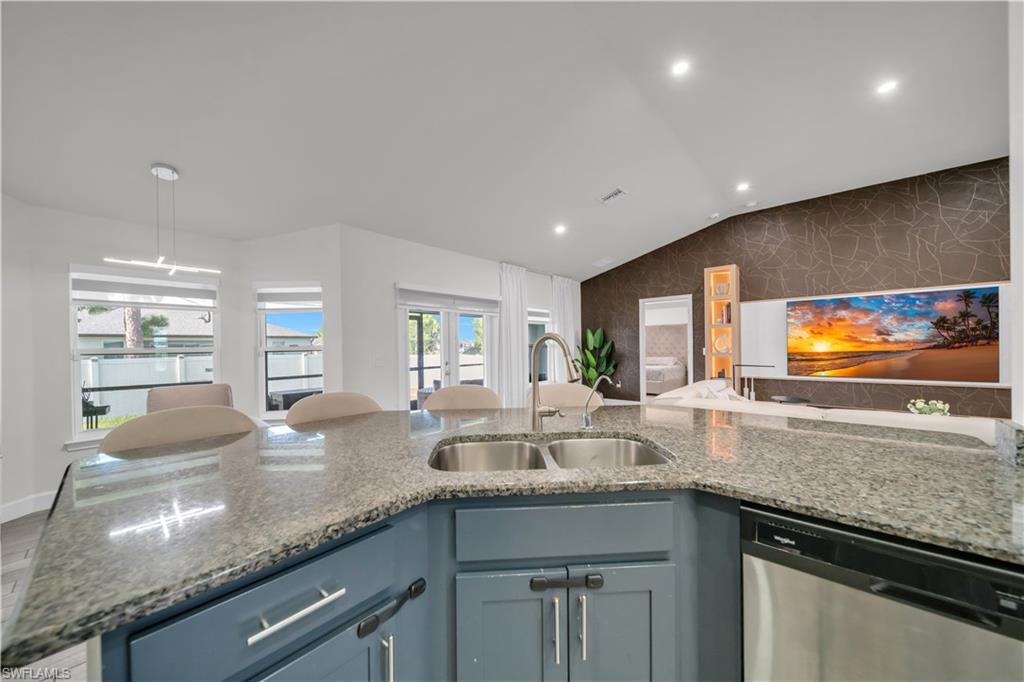 Kitchen island featuring a dual basin stainless steel sink, a stainless steel dishwasher, and granite countertops