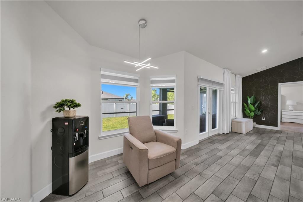 Wood-finish tile flooring, modern linear pendant lighting, double French doors, large bay windows, and a decorative accent wall