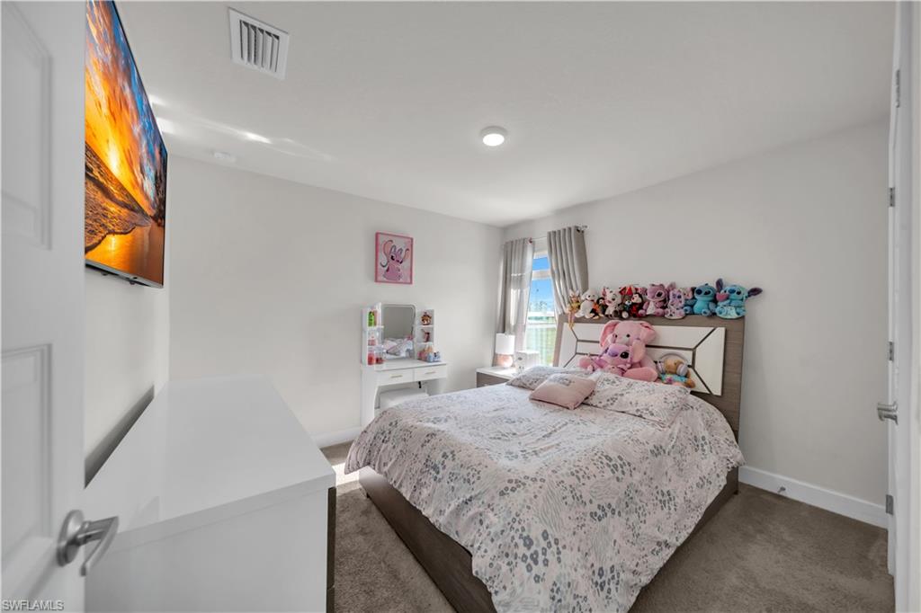 Neutral wall color, recessed ceiling lighting, wall-mounted television, window with vertical blinds, and carpeted flooring