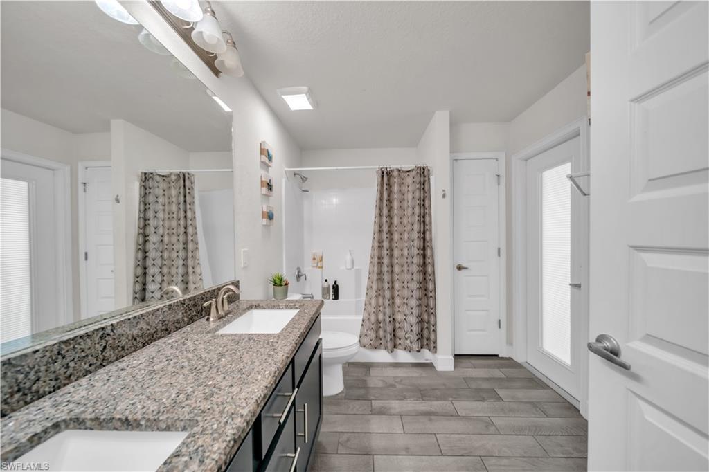 Dual vanity with integrated sinks, speckled countertop, and wood-finish flooring
