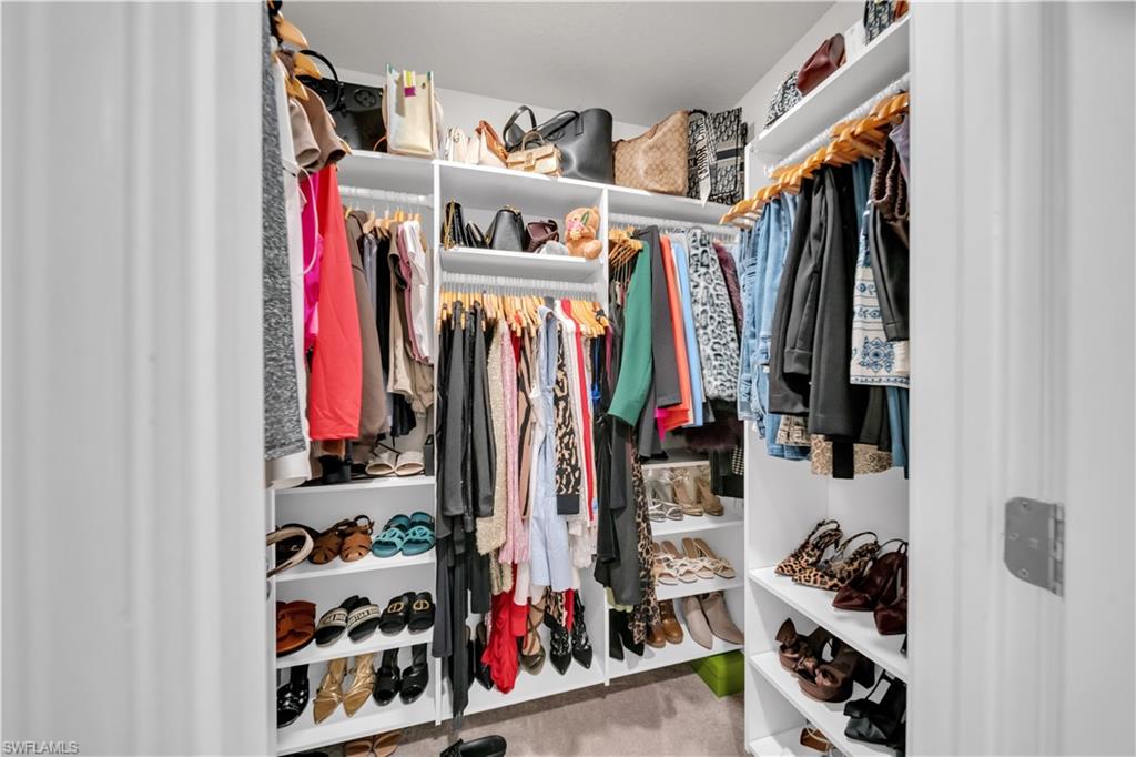 Walk-in closet with extensive built-in shelving, multiple hanging rods, and integrated shoe storage