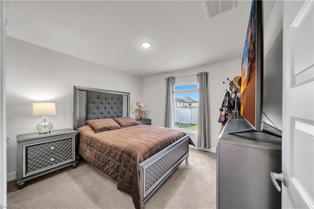 Recessed lighting, light-toned carpeting, and a window with a white privacy screen