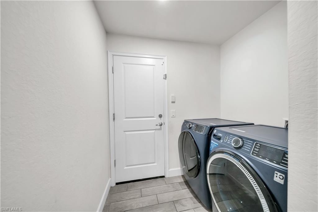 Utility space featuring light-toned walls, a white paneled door, and wood-finish flooring
