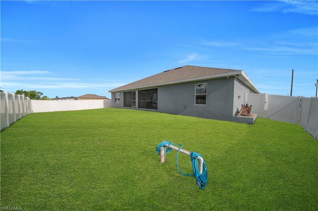 Expansive green lawn, full perimeter fencing, and screened patio area