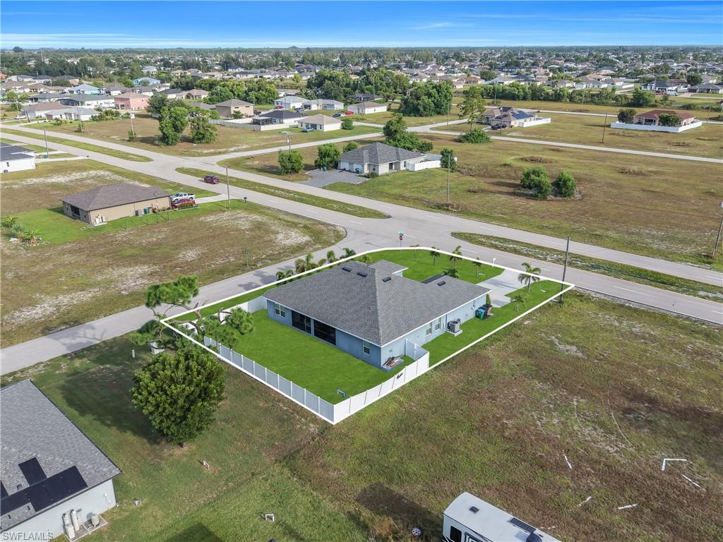 Single-story residence on a corner lot, featuring a fenced yard with a manicured lawn, a concrete driveway, and mature landscaping