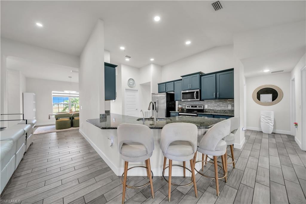 Kitchen featuring an expansive island with a countertop, recessed lighting, and wood-finish flooring