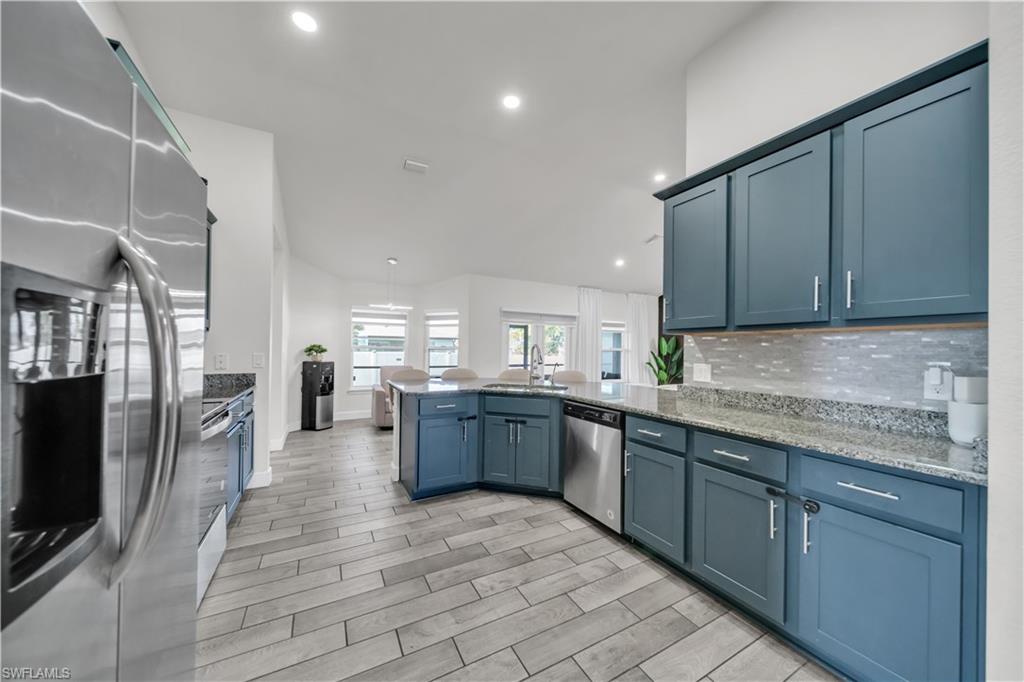Kitchen featuring blue cabinetry, stainless steel appliances, granite countertops, and tiled backsplash