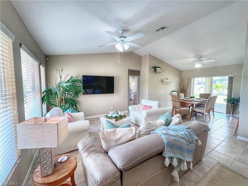 Tiled living room with lofted ceiling and a ceiling fan