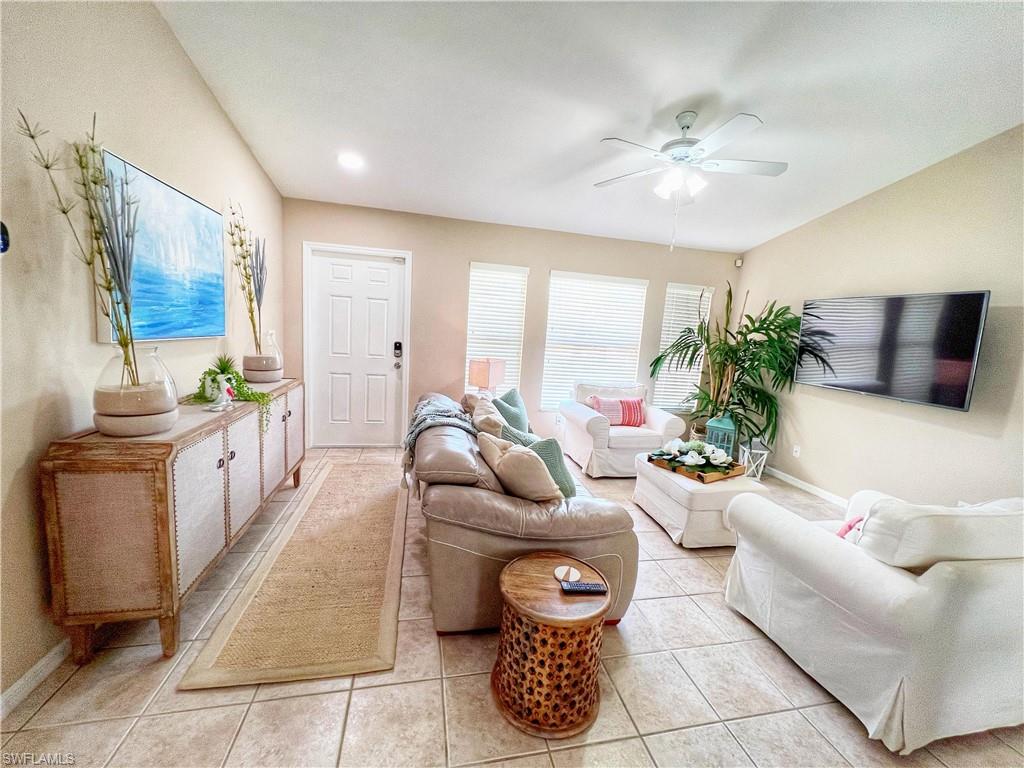 Living area featuring light tile patterned floors and ceiling fan