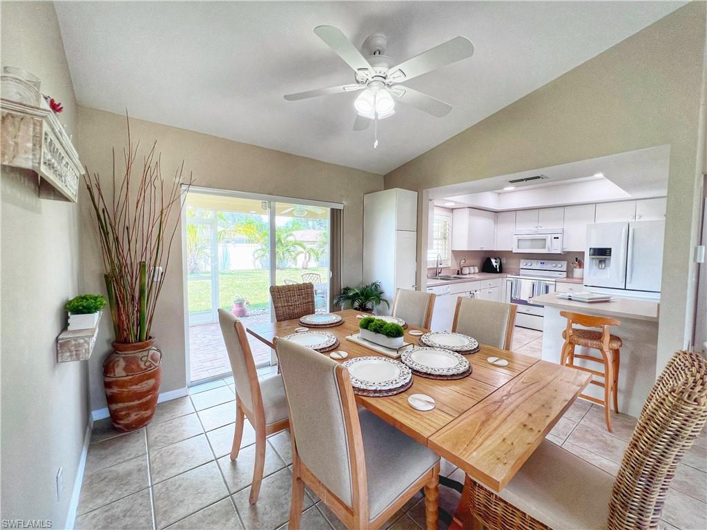 Dining area featuring light tile patterned floors, vaulted ceiling, and ceiling fan