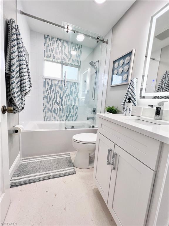 Bathroom featuring vanity and shower / bath combination with glass door