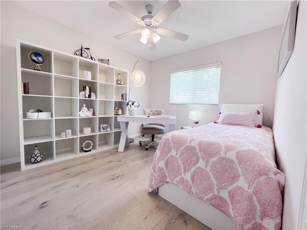 Bedroom with light wood finished floors, an office area, and ceiling fan