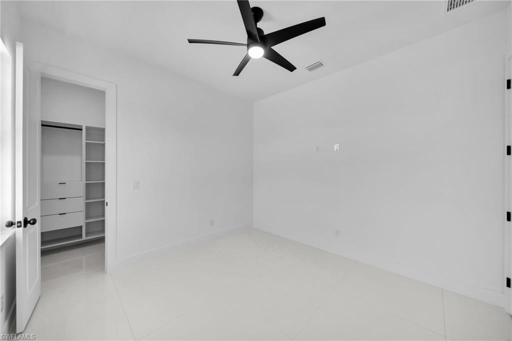 Bedroom #3: Recessed lighting, modern ceiling fan, white tile flooring, built-in closet shelving, and a built-in closet drawer system