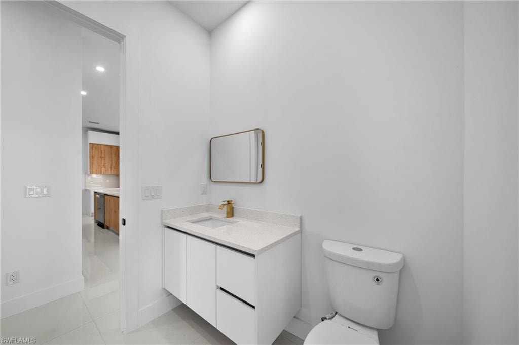 Bathroom #2: Vanity with a light-toned countertop, white cabinetry, and gold-finish faucet