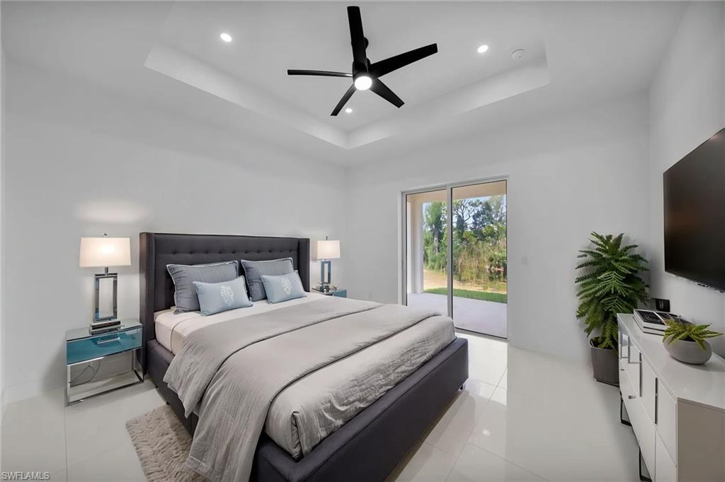 Primary Bedroom virtually staged: Recessed lighting with a ceiling fan, tray ceiling, sliding glass door, and large format floor tiles