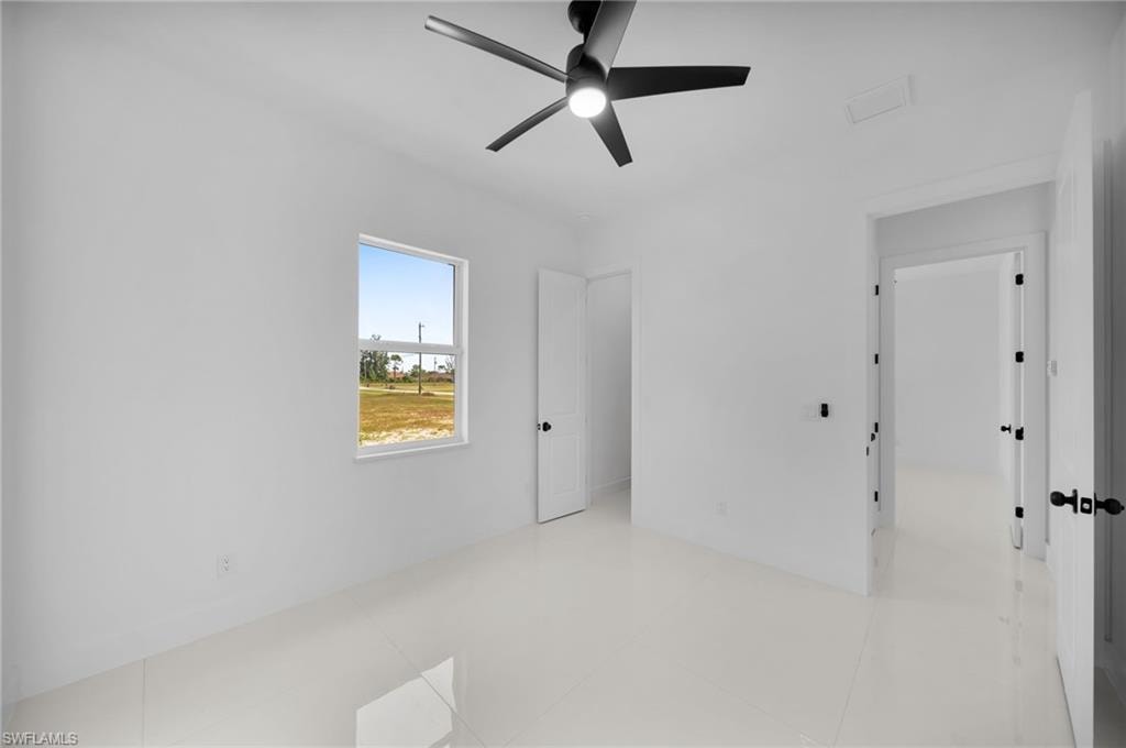 Bedroom #2: Clean white walls, window with outdoor scenery, recessed lighting, matte black ceiling fan, and light-toned tile flooring